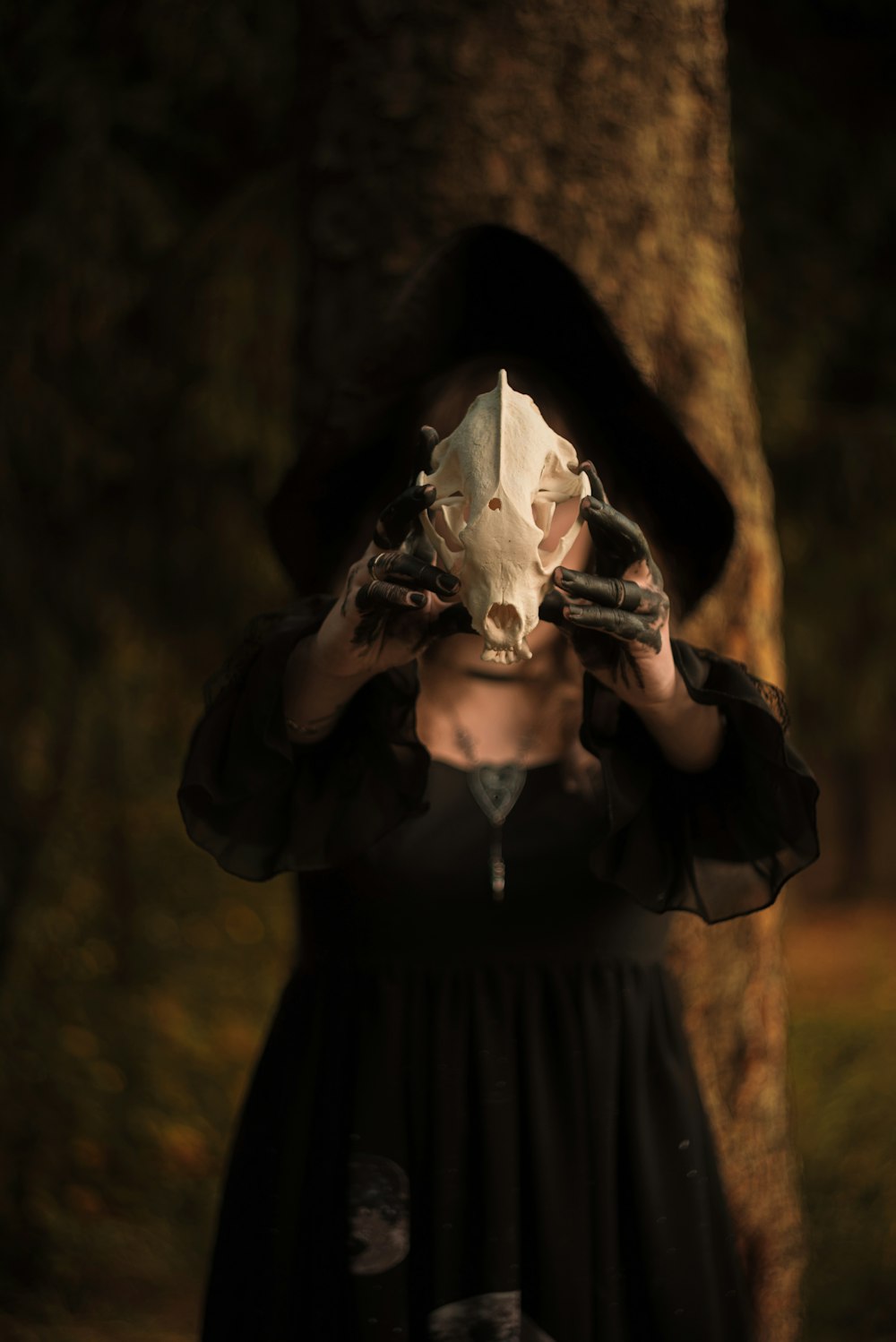 person in black jacket holding white skull