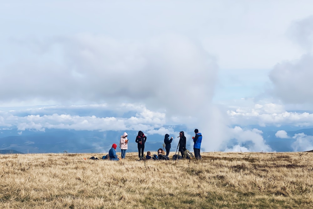 people on green grass field under white clouds during daytime