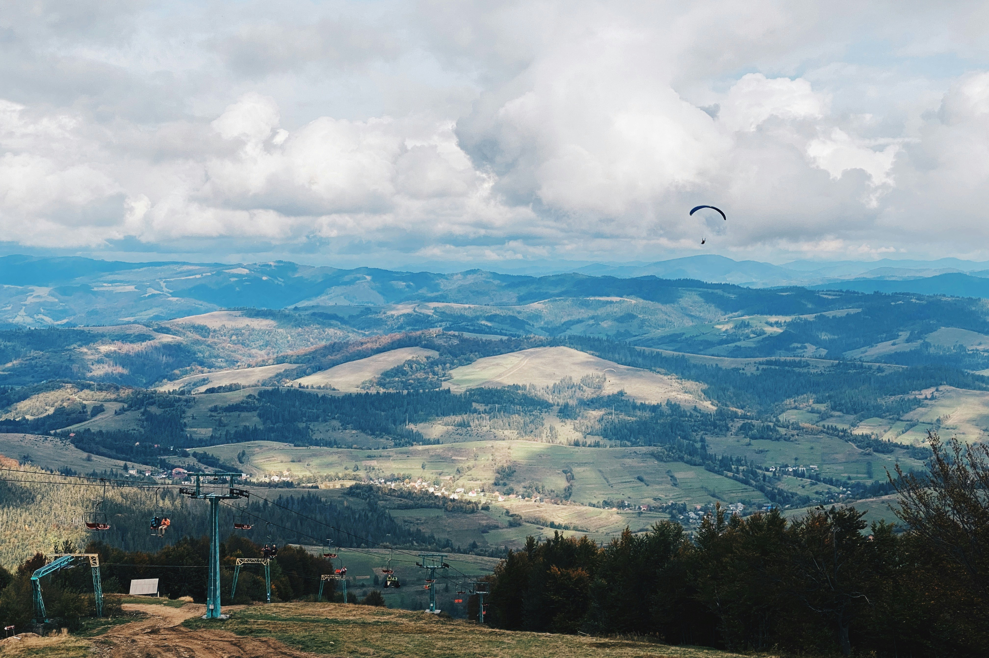 white clouds over green trees and mountains