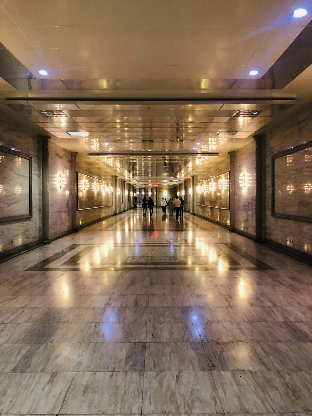 people walking on hallway with lights turned on during nighttime