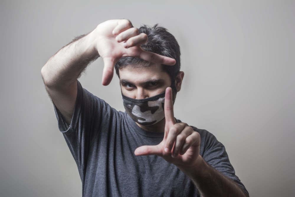 Hombre con camiseta negra de cuello redondo que se cubre la cara con la mano