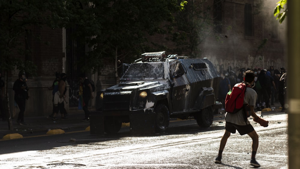 man in red jacket standing beside black suv during daytime