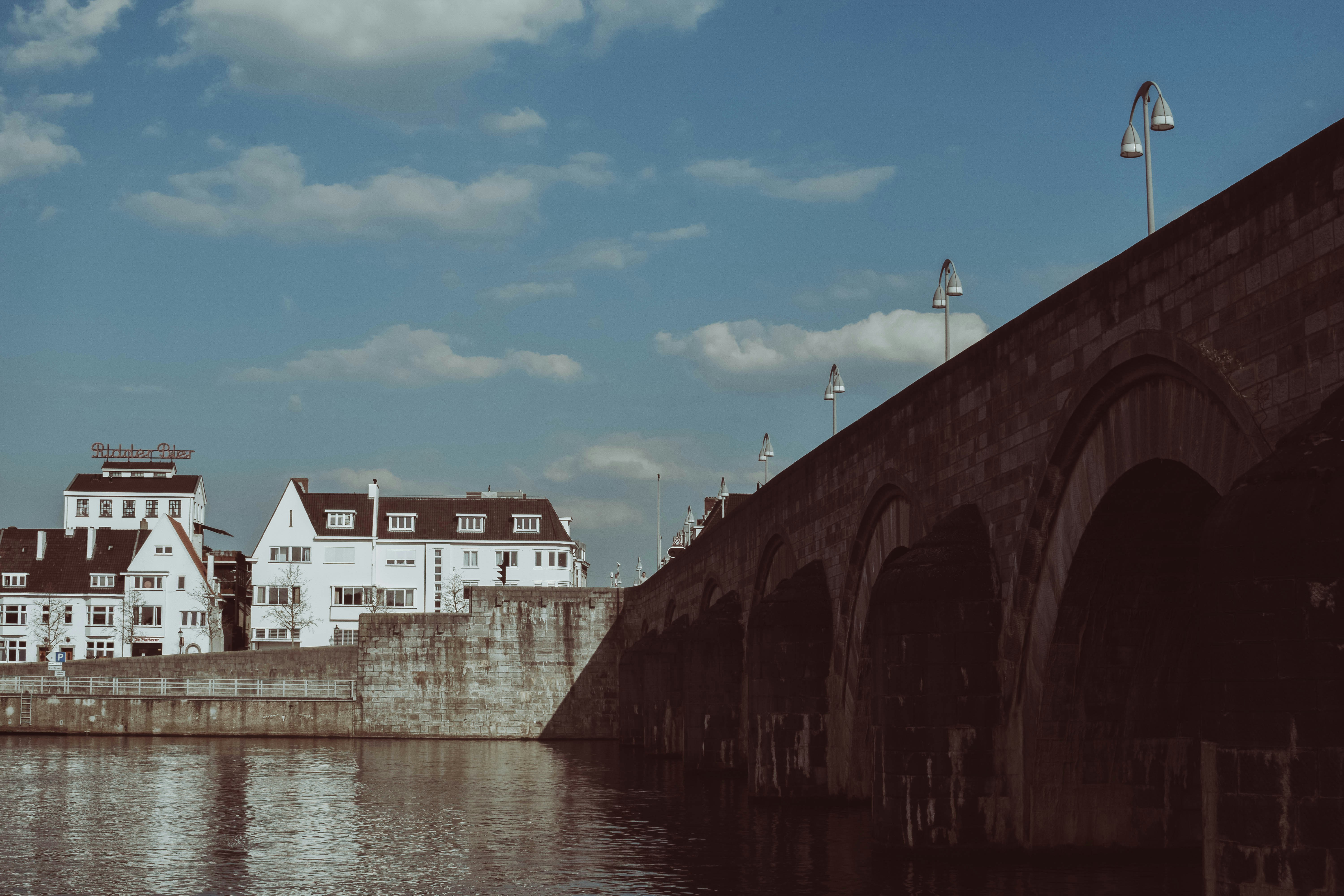 Edificio de hormigón blanco y marrón junto al río bajo el cielo azul durante el día