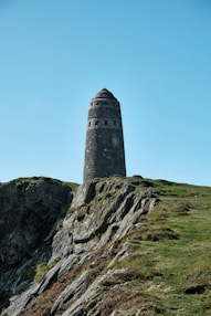 gray concrete tower on green grass field under blue sky during daytime