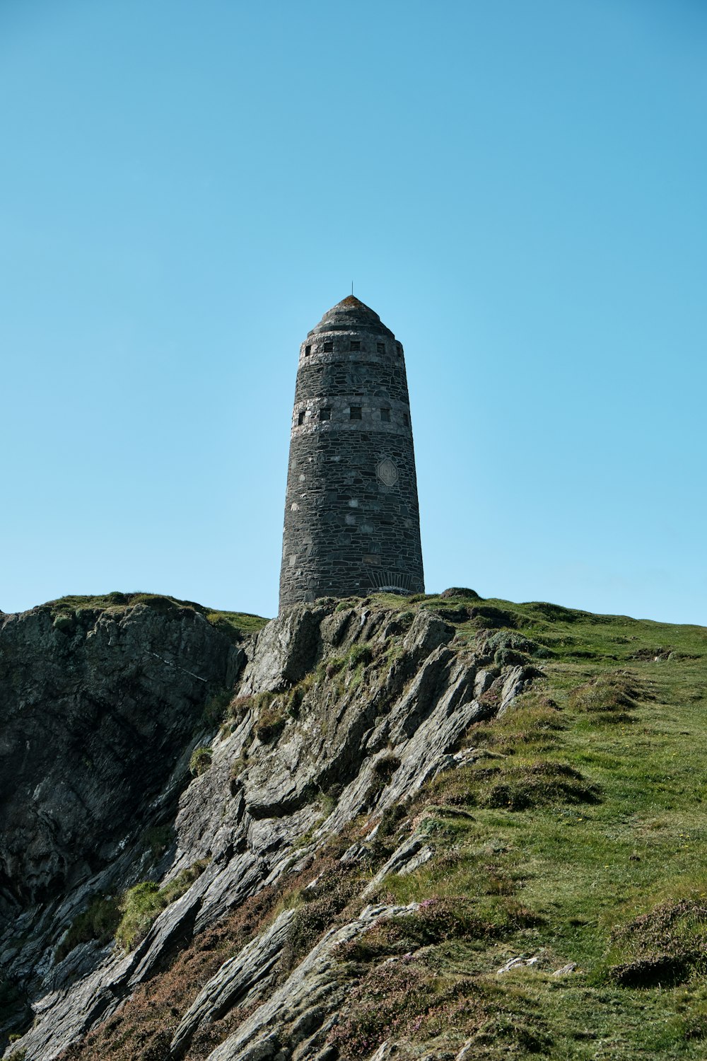 gray concrete tower on green grass field under blue sky during daytime