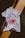 A white t-shirt is laid over a tiled surface that consists of black and yellow tiles. The t-shirt has a graphic design featuring a red circular image resembling a celestial body, along with some text and arrows.