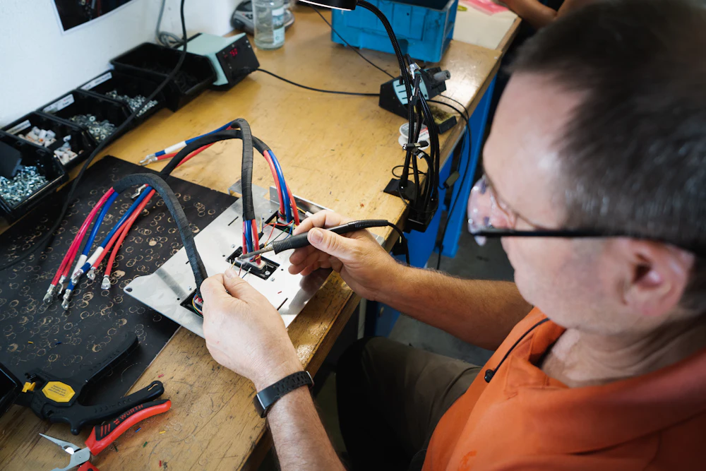 A repairman in glasses working carefully at his electronics bench