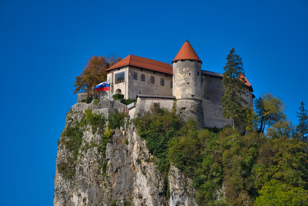 brown and white concrete building on top of green and brown mountain under blue sky during