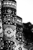 Detailed black and white close-up of a richly patterned knitted fabric with an intricate design that includes geometric shapes and symmetrical motifs.