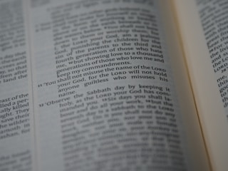 A close-up of an open Bible showing a passage with numbered verses. The focus is on verse 11, which discusses the use of the Lord's name. The text appears in two columns with a slight tilt.