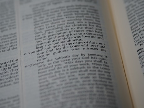 A close-up of an open Bible showing a passage with numbered verses. The focus is on verse 11, which discusses the use of the Lord's name. The text appears in two columns with a slight tilt.