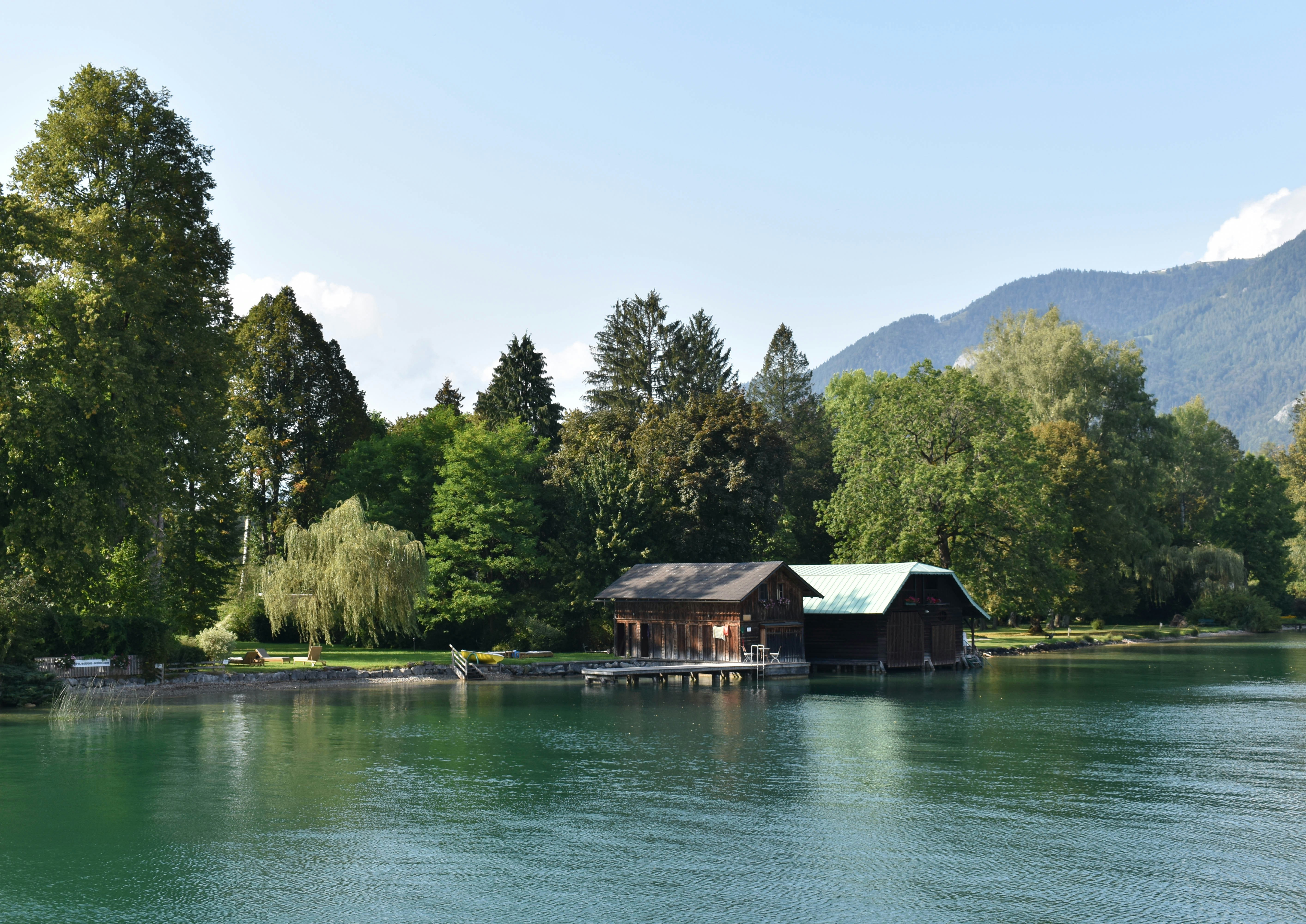 brown wooden house on lake near green trees during daytime österreich teams background
