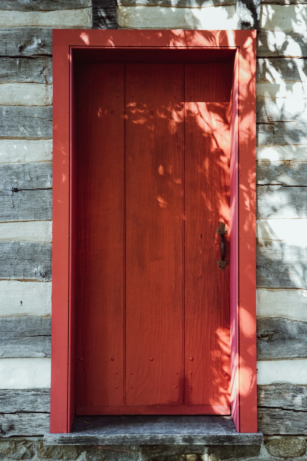 red wooden door with white concrete wall