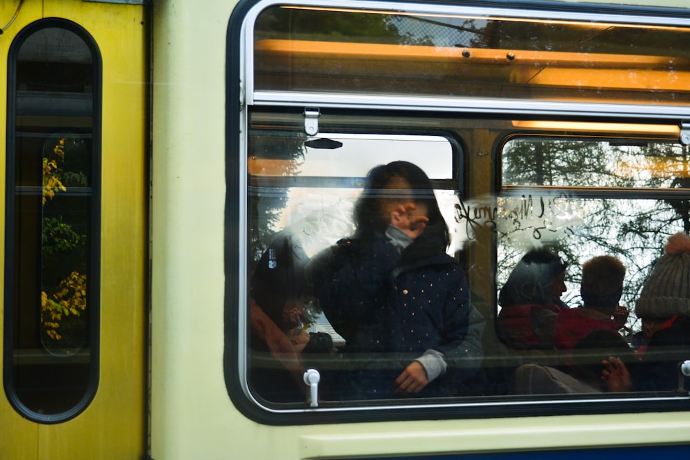 man in black jacket sitting inside yellow and white train