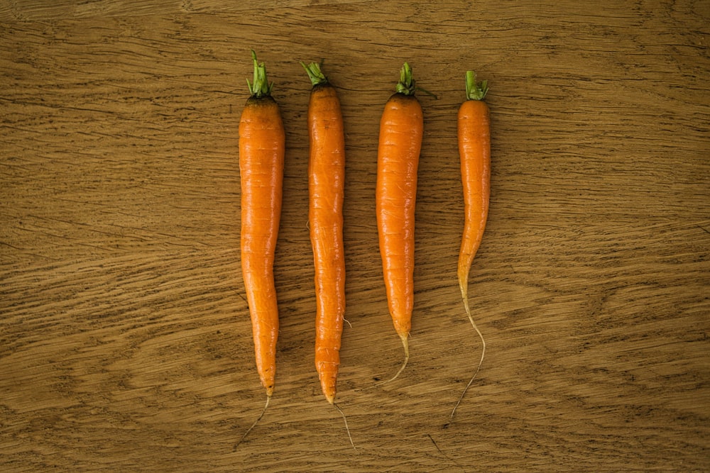 three orange carrots on brown wooden table