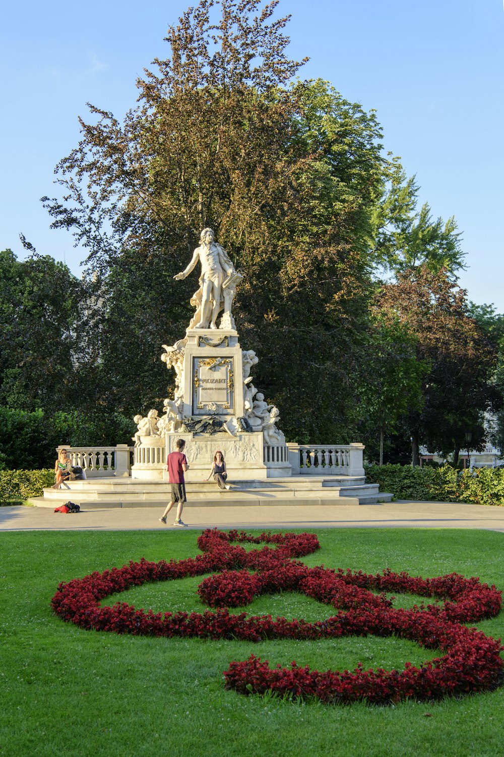 people walking on park with statue of woman