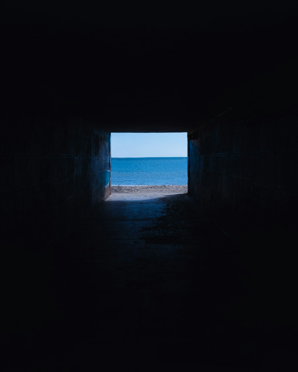 gray concrete tunnel near sea during daytime