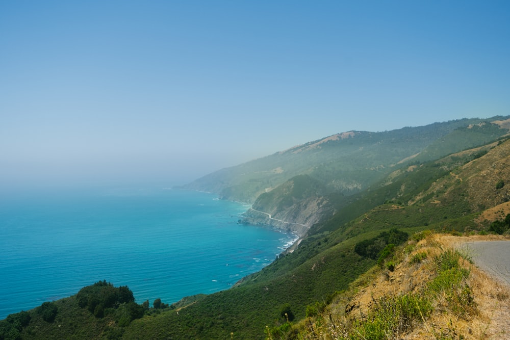 green mountain beside blue sea under blue sky during daytime