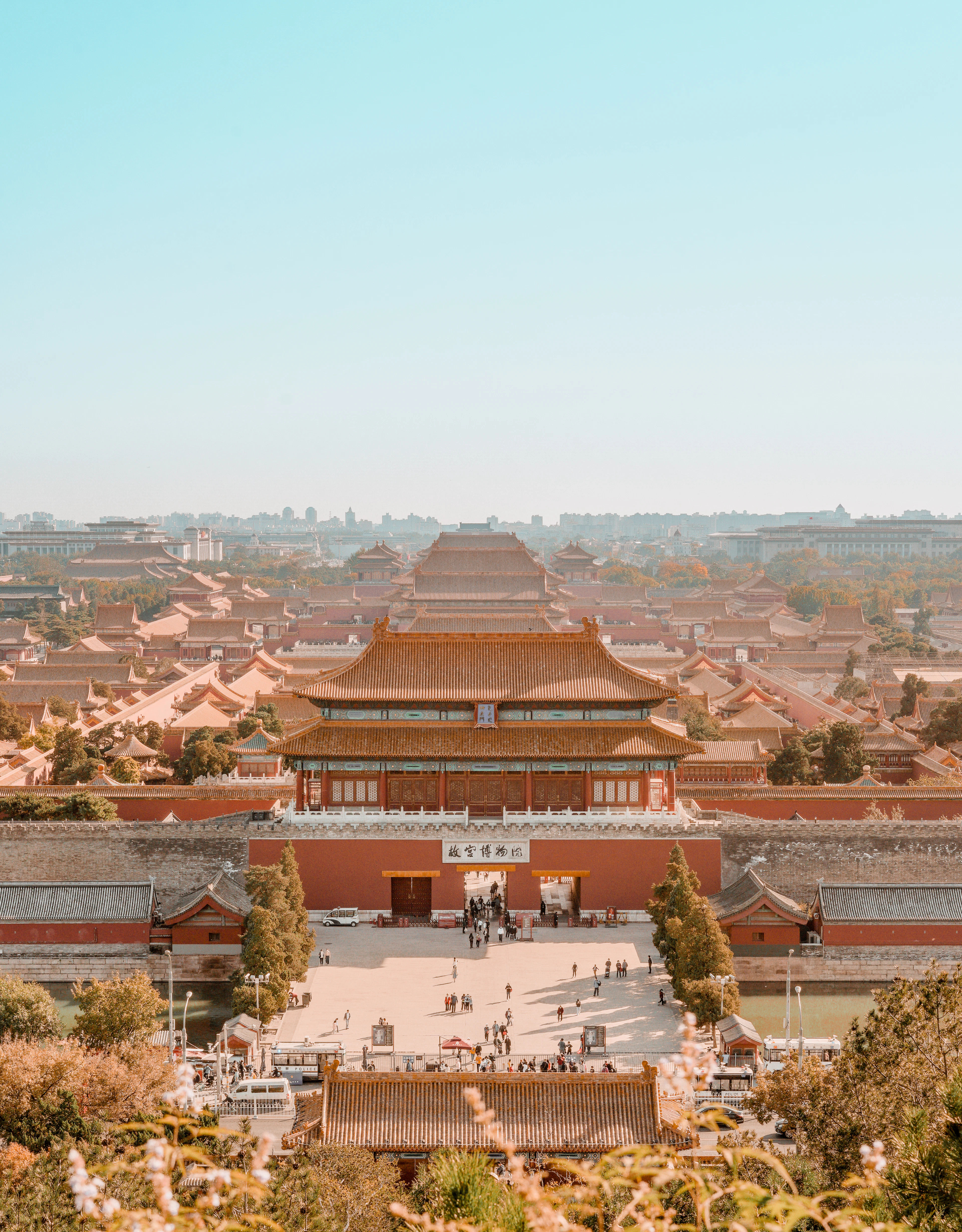 The Forbidden City in Beijing seen from the hill in Jingshan Park, the Gate of Divine Prowess in the foreground and rank after rank of golden tiled roofs stretching away into soft autumn haze