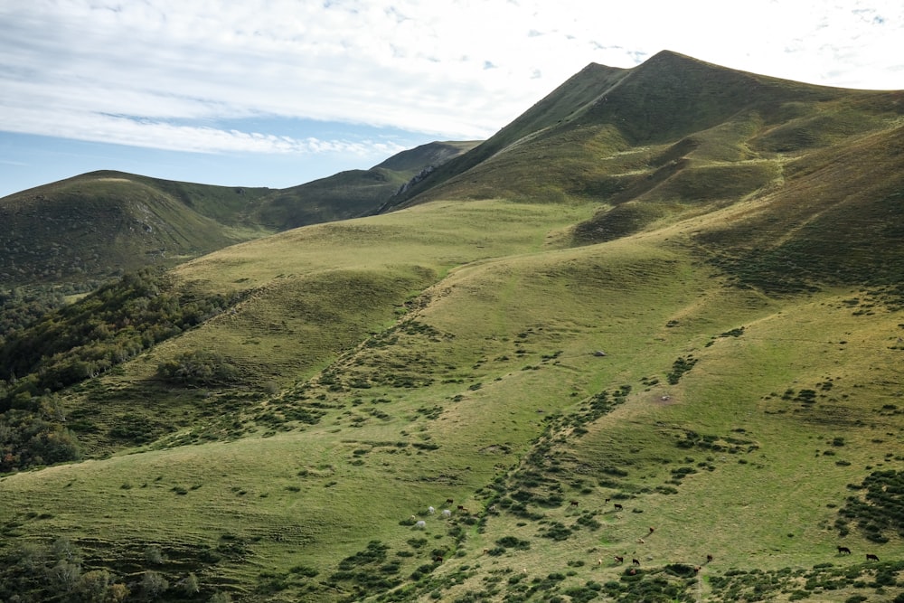 montagnes vertes et brunes sous des nuages blancs pendant la journée