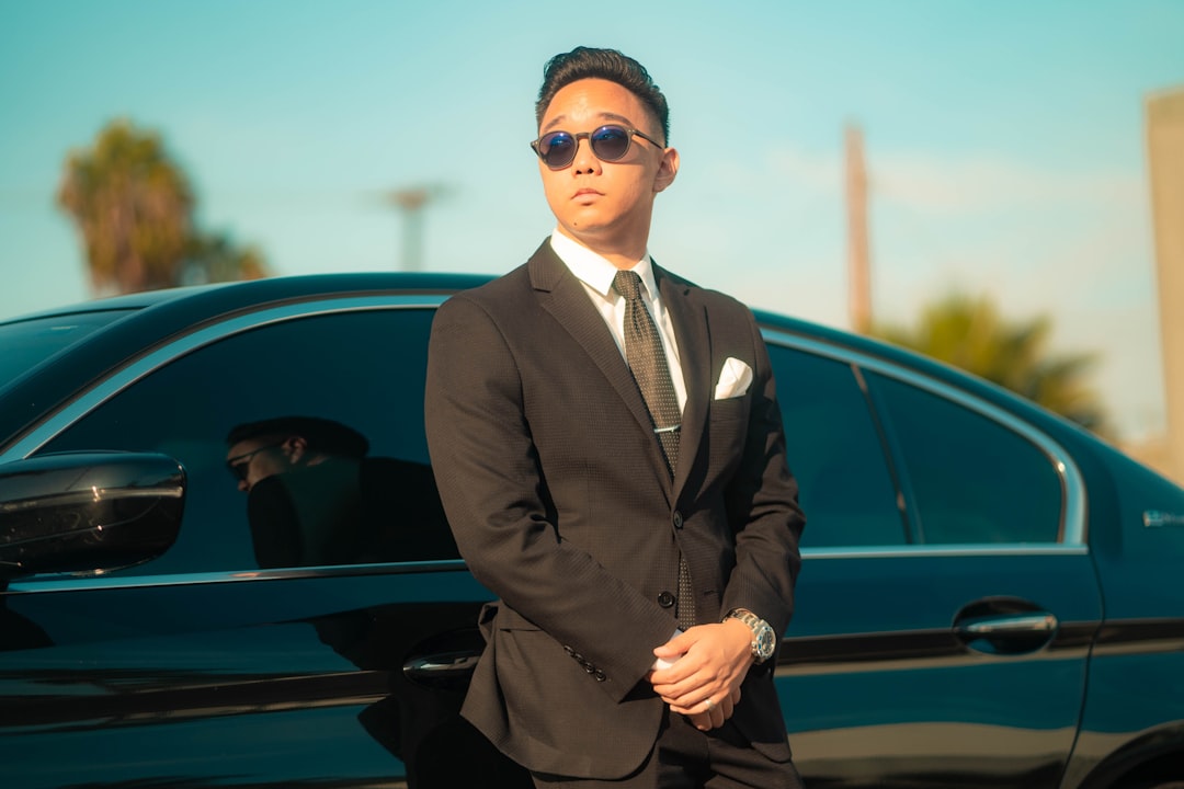 man in black suit standing beside black car during daytime