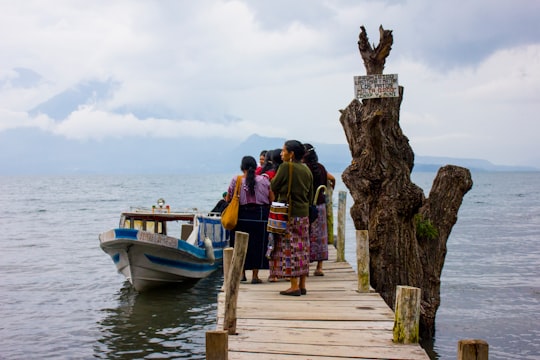 people standing on wooden dock near body of water during daytime in Lake Atitlán Guatemala