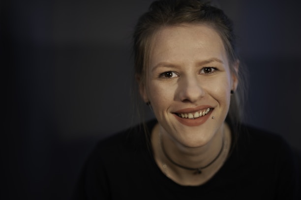 A smiling client showing off her new ear piercing in a cozy studio environment.