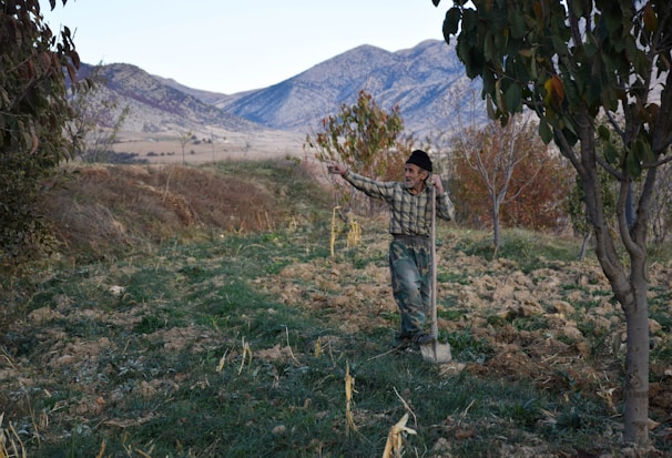 An elderly man receiving assistance from a volunteer in a rural area.