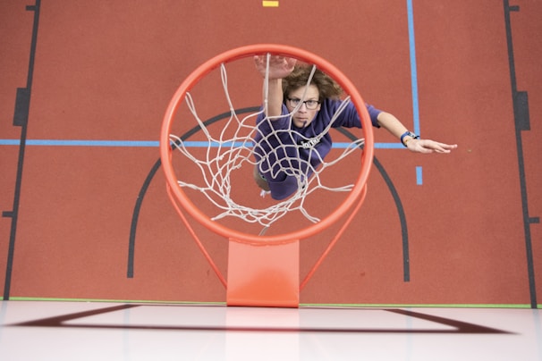 Dynamic photo of a basketball player sprinting down the court in a black and red apace athletics uniform.