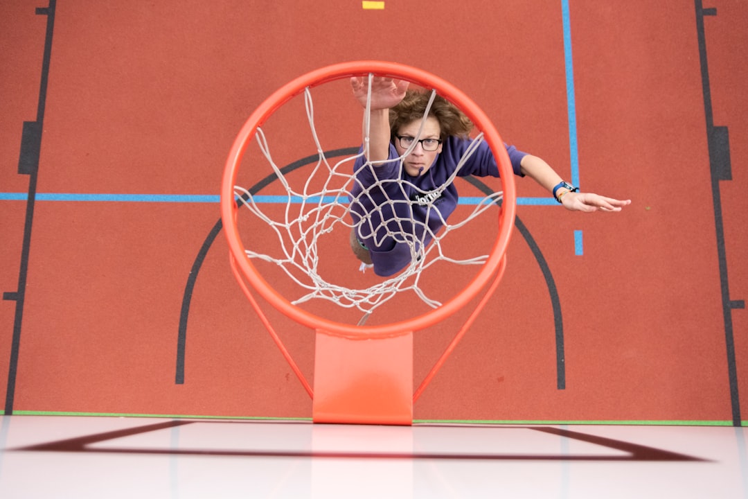 woman in black shirt sitting on basketball hoop