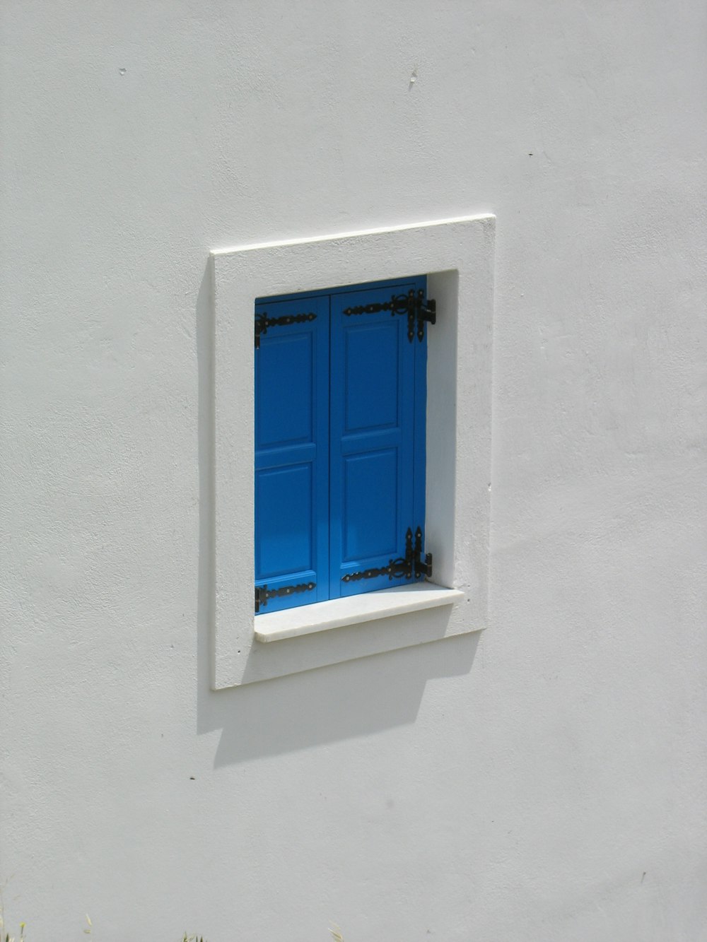 blue wooden window on white concrete wall