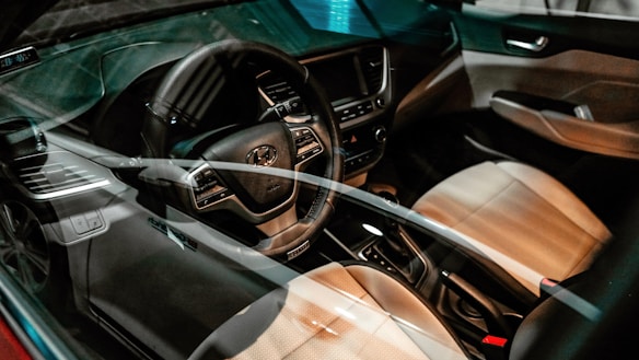 The image captures the interior of a car, showcasing the steering wheel, dashboard, and front seats. The car appears modern and well-maintained, with a focus on the steering wheel area, which has visible control buttons. The dashboard has a digital display and air vents.