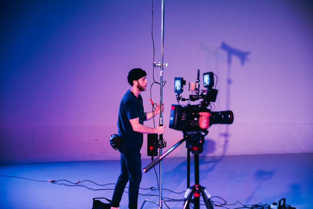 homme en chemise bleue et pantalon noir debout sur un microphone noir