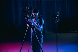 man in white t-shirt holding black dslr camera