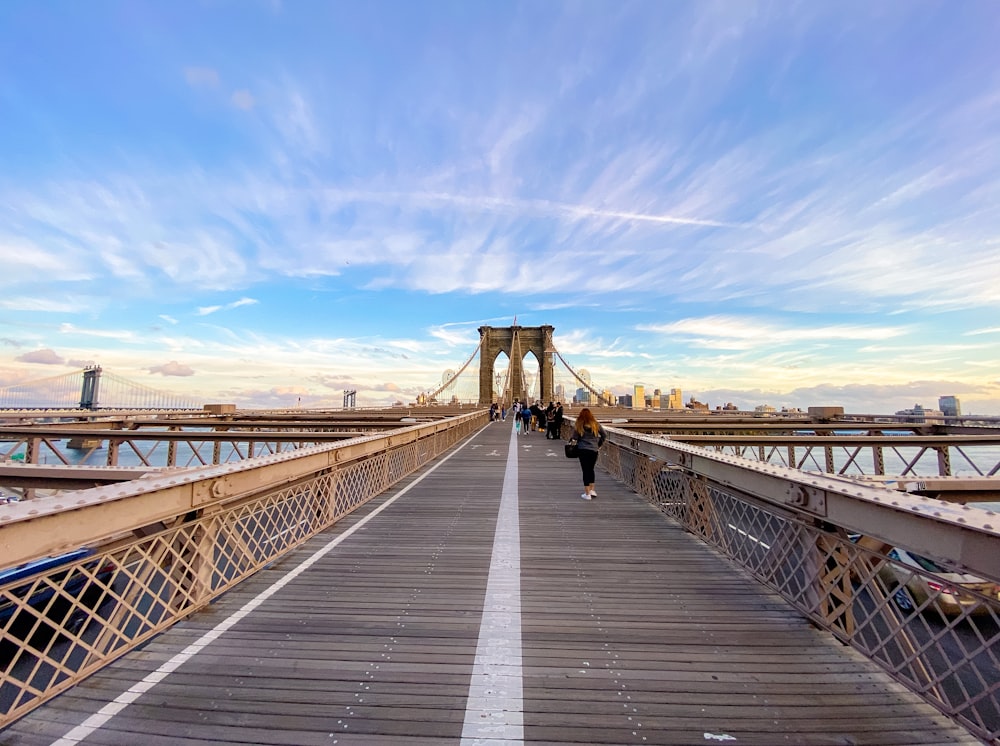 people walking on bridge under blue sky during daytime