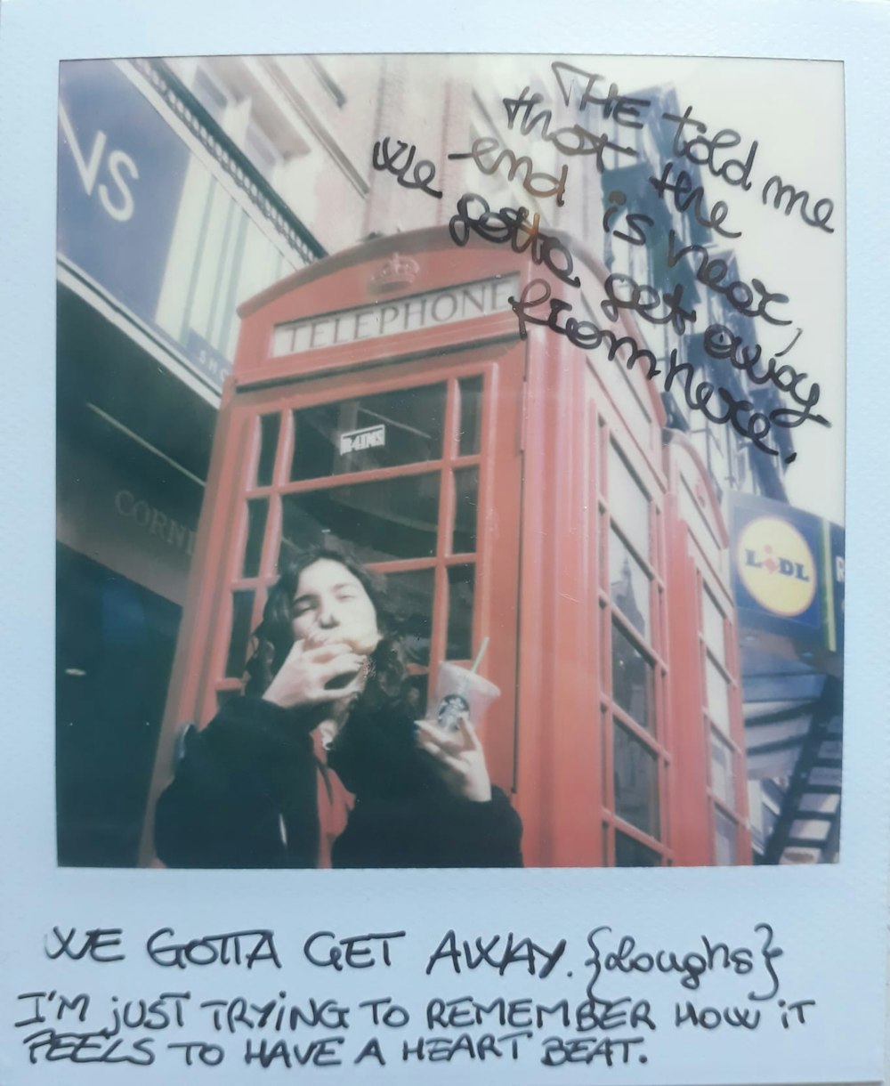 woman in black jacket standing near red telephone booth