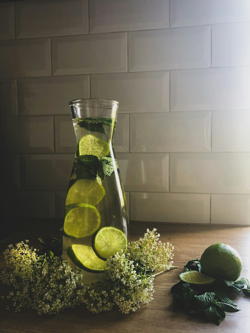lime juice in clear glass pitcher beside sliced lemon