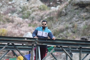 man in blue jacket sitting on red metal railings during daytime