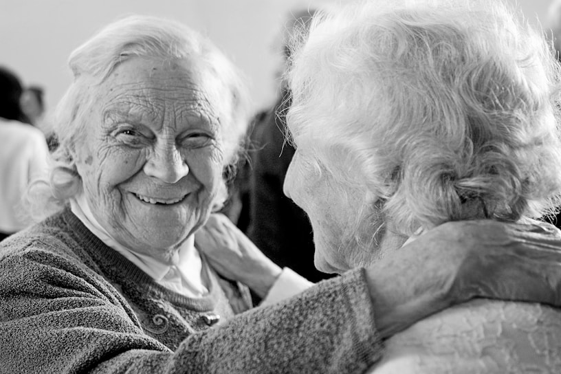 A warm moment of an elderly woman smiling while holding hands with her caregiver at home.