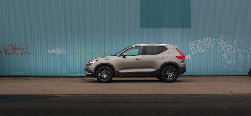 gray suv parked beside blue wall