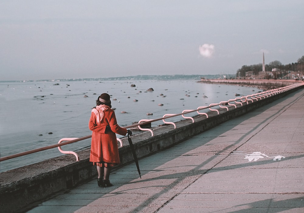 woman in red dress walking on dock during daytime