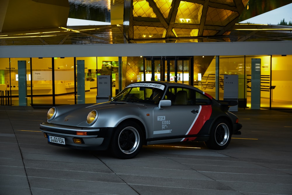 Porsche 911 grise et rouge garée dans l’immeuble