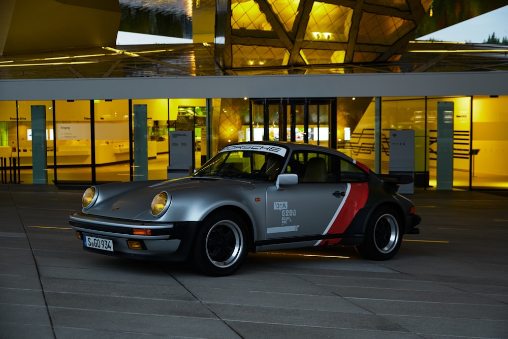 Porsche 911 gris y rojo aparcado en un edificio