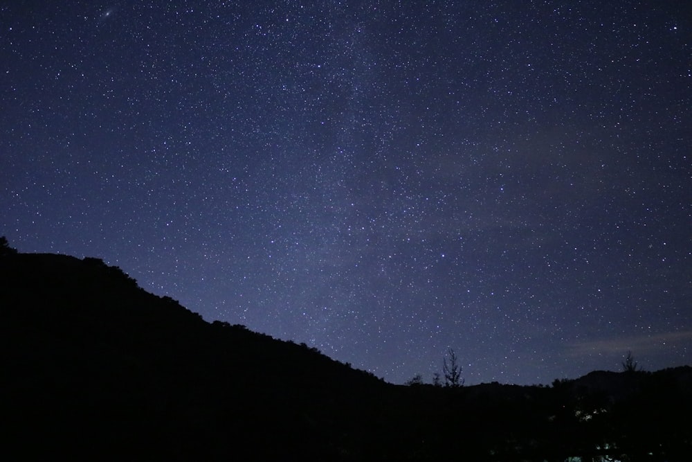 silhouette of mountain under starry night