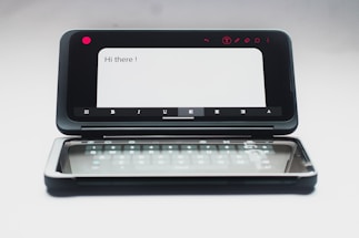 A dual-screen smartphone with one screen displaying a message saying 'Hi there!' and the second screen showing a virtual keyboard. The device is in an open position, and the background is neutral, enhancing the focus on the smartphone.