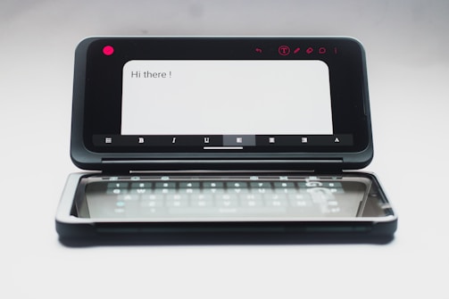 A dual-screen smartphone with one screen displaying a message saying 'Hi there!' and the second screen showing a virtual keyboard. The device is in an open position, and the background is neutral, enhancing the focus on the smartphone.