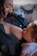 A tender moment between a mother and her baby as she breastfeeds. The mother is wearing a denim shirt and is smiling as she gazes at the baby, who is wrapped in white clothing and looking up at her.