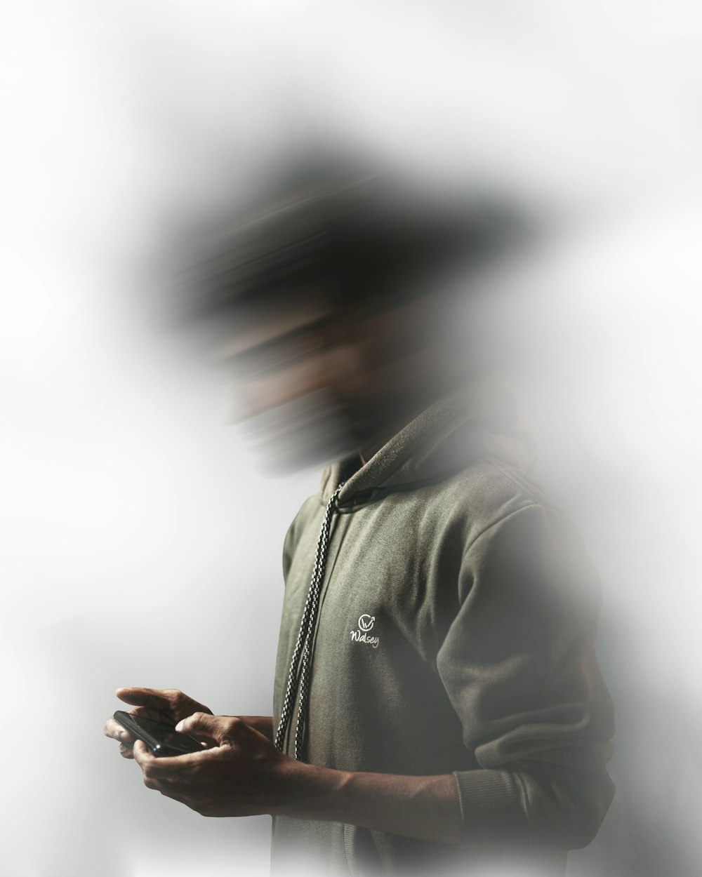 uomo in felpa con cappuccio grigia usando lo smartphone