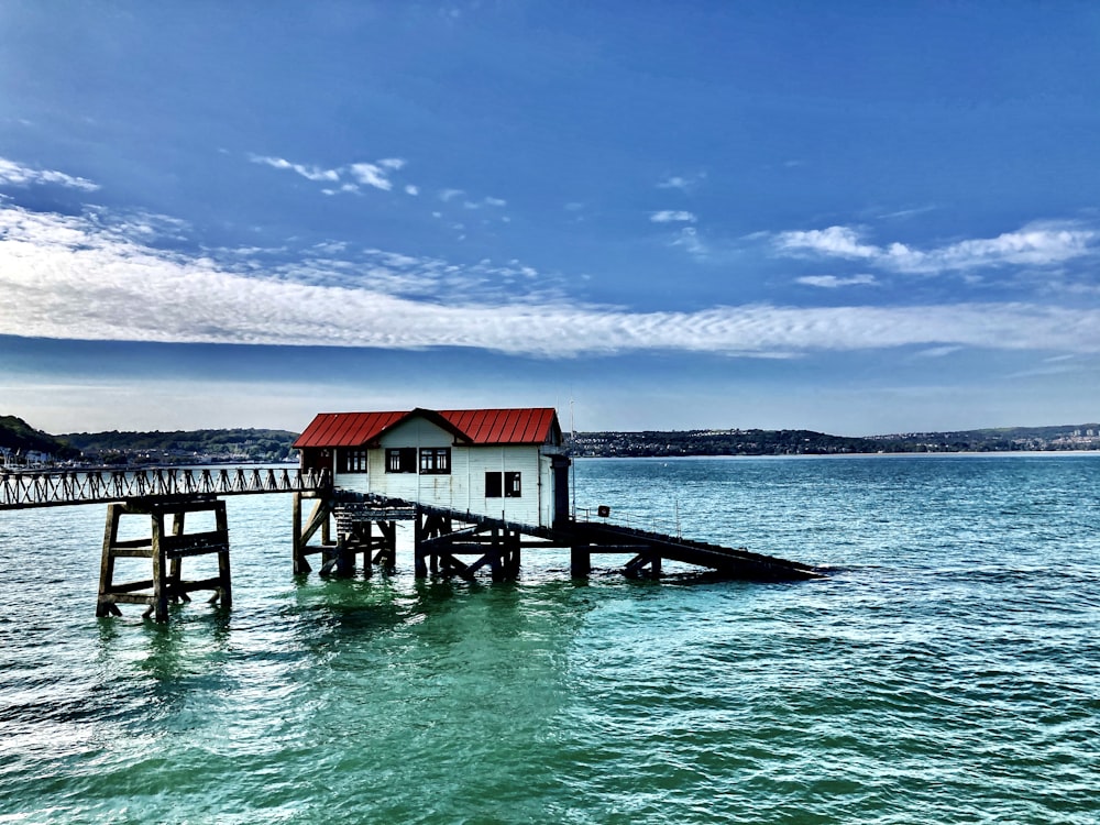 white and red wooden house on sea under blue sky during daytime