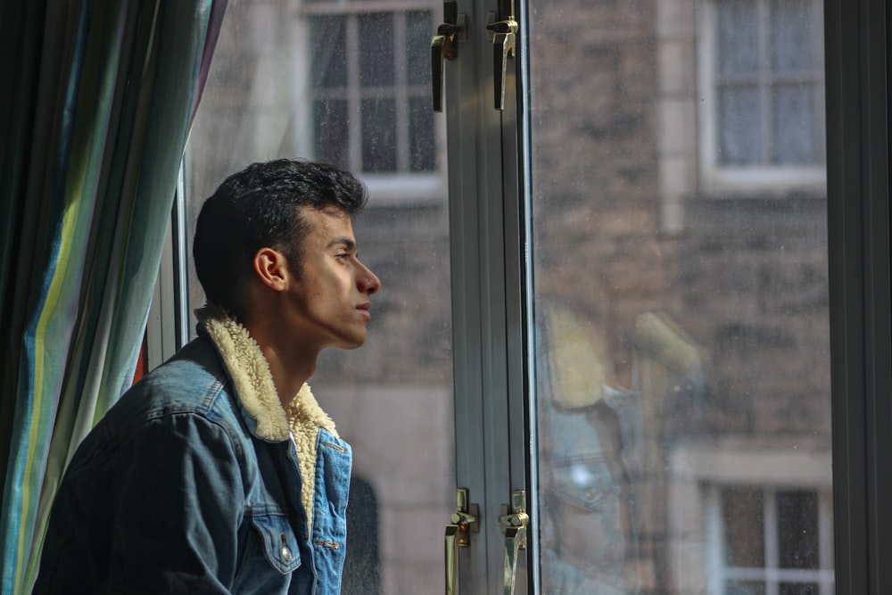 man in black jacket looking out the window